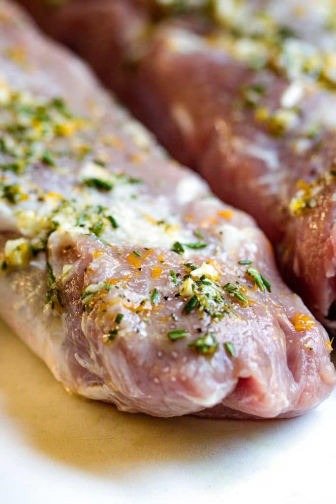close up: minced garlic and herbs on raw pork tenderloin