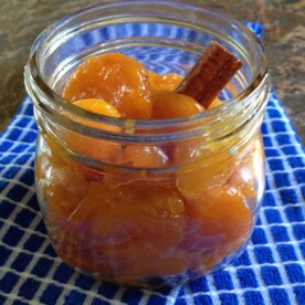 A glass of poached apricots with cinnamon stick