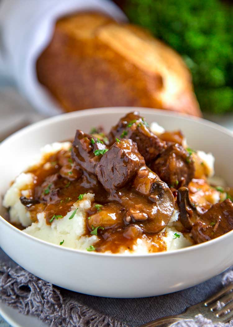 bowl of beef bourguignon served over fluffy mashed potatoes