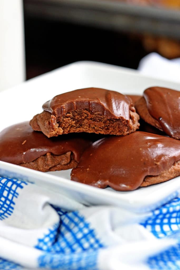 stacked of chocolate frosted cookies on white plate