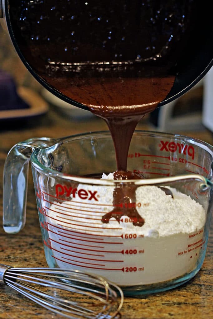 pouring melted chocolate mixture into bowl of flour