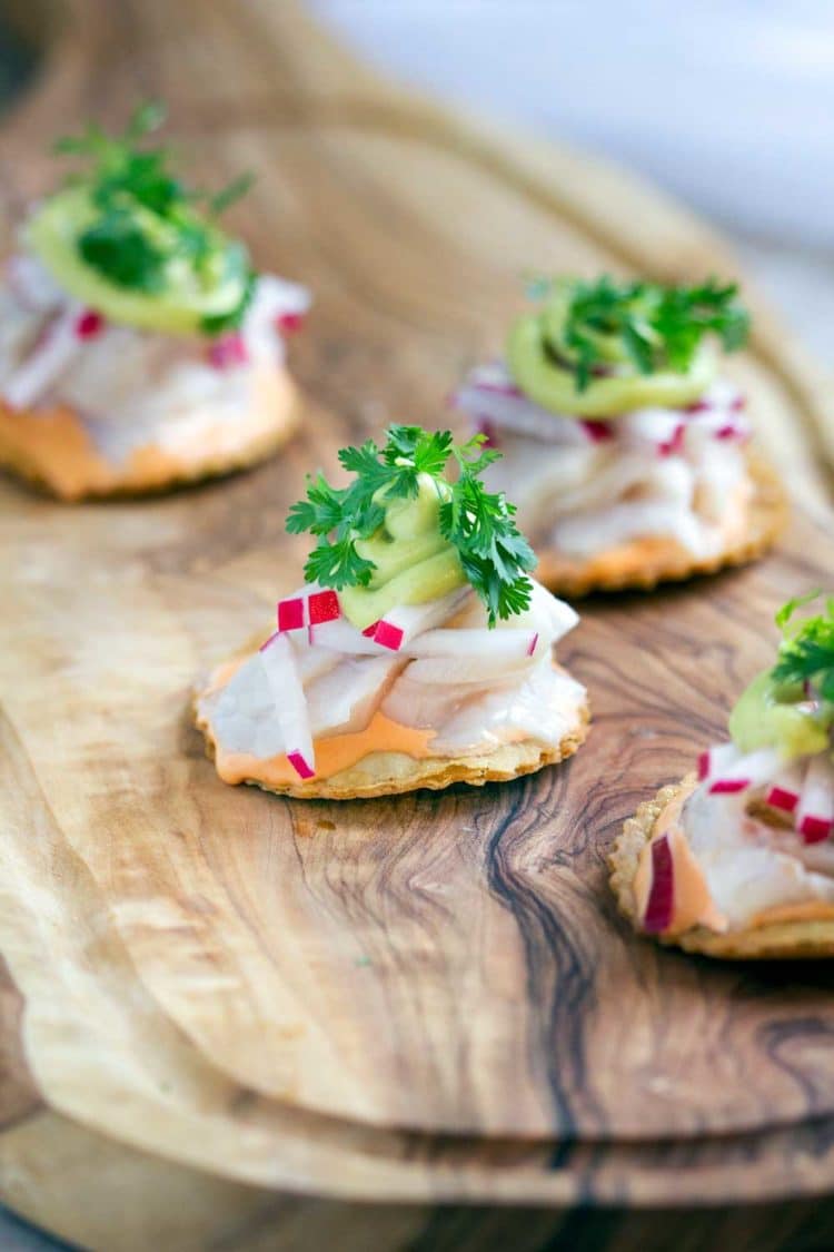 several ceviche tostadas on a wooden cutting board