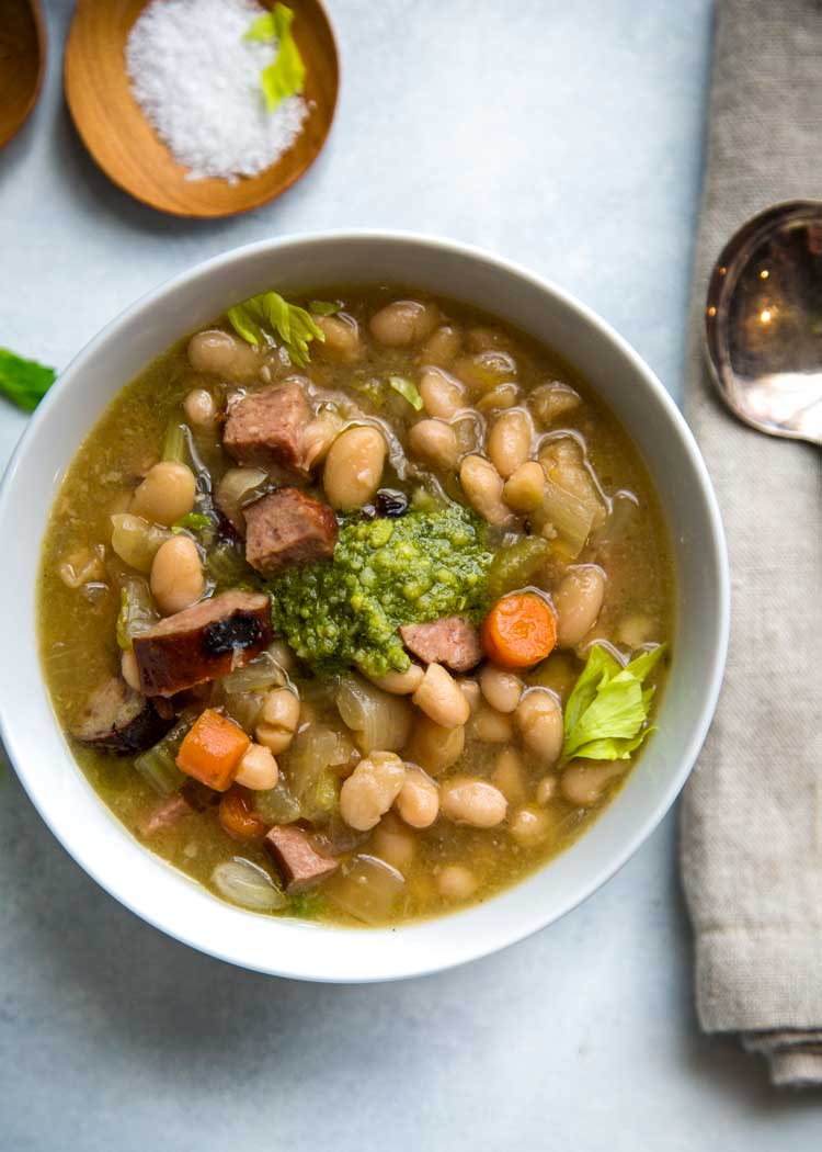 This Slow Cooker White Bean Soup has added beef kielbasa sausage for a heartier meal. Grilled or pan seared for that added caramelization flavor, plus a touch of fresh pesto tops it all before serving. www.keviniscooking.com