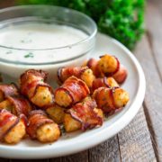 A bowl of ranch dressing and Bacon wrapped tots