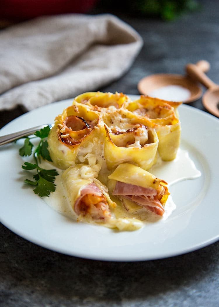 Ham and Cheese Pasta Roll ups on plate with garnish and cream sauce
