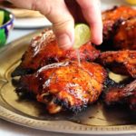 squeezing lime over barbecued chicken thighs