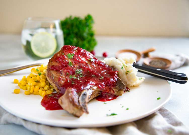 Cranberry Glazed Pork Loin Chops get seared and roasted to juicy perfection. The cranberry glaze includes honey, fresh ginger, orange juice and a chile. keviniscooking.com