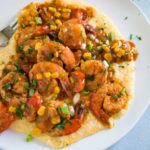 close up image: plate of cheesy grits topped with creole style shrimp
