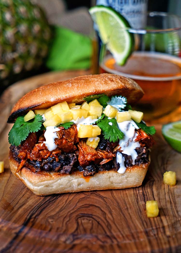 pineapple pork on ciabatta roll with glass of mexican beer