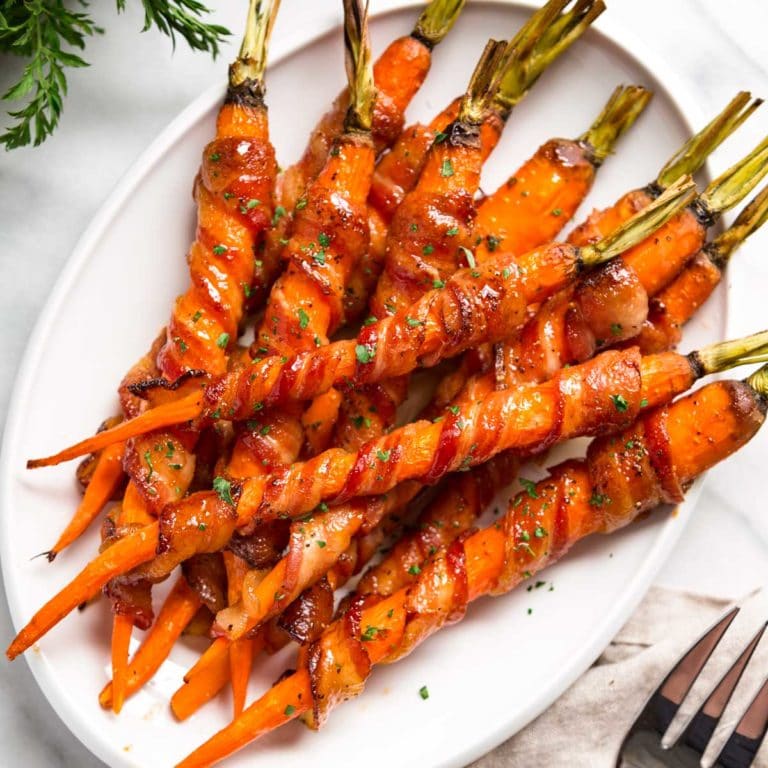These amazing Maple Glazed Carrots get bacon wrapped, sprinkled with black pepper and roasted, then basted with a maple Sriracha sauce. So easy and good! keviniscooking.com