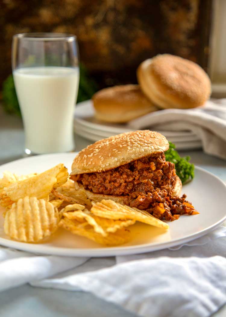 plated loose beef sandwich with chips and glass of milk