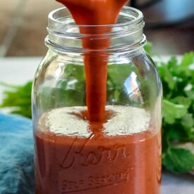 pouring authentic enchilada sauce into canning jar