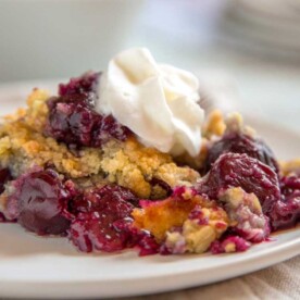 plate of cherry crisp with whipped cream