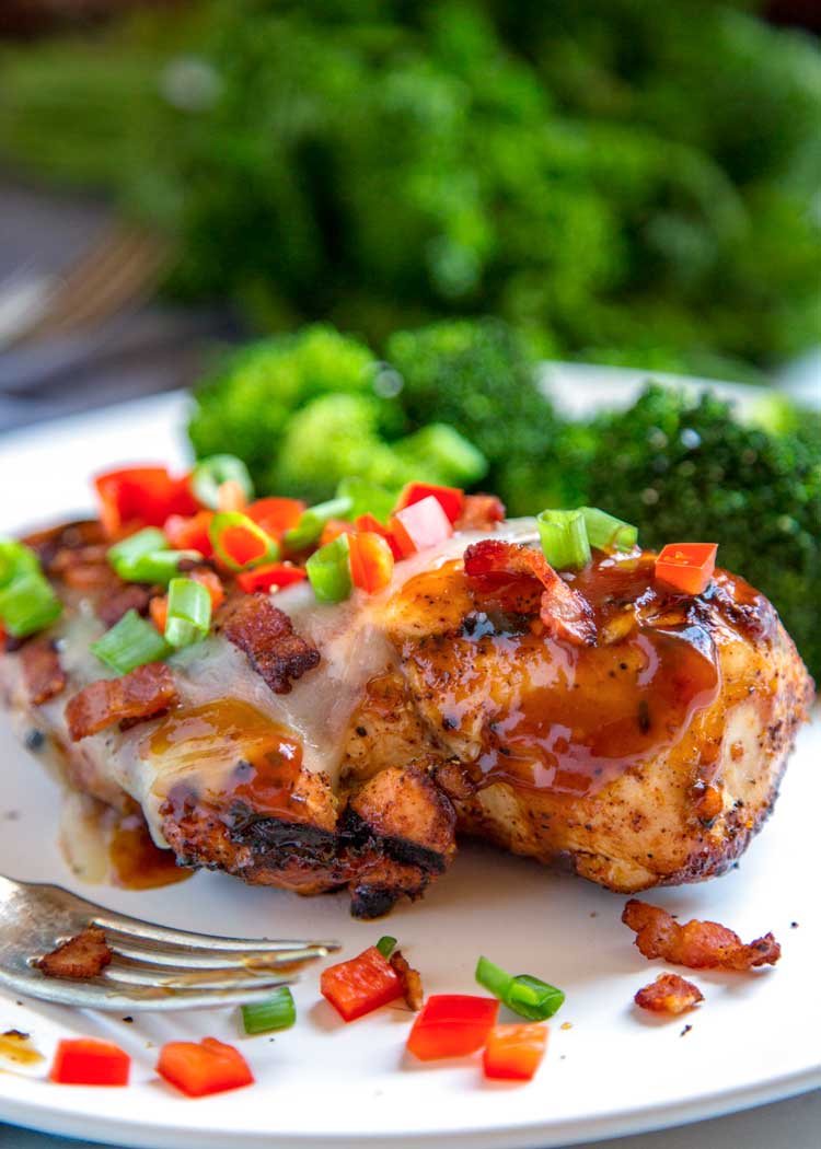 Grilled Monterey Chicken on a white plate garnished with diced red and green bell peppers