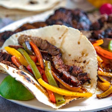 A Tex Mex favorite and staple at many restaurants, Grilled Steak Fajitas are the perfect blend of well seasoned steak charred with bell peppers and onions all wrapped in a warm tortilla.