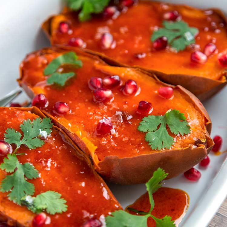 A plate of sweet potatoes with honey butter glaze and pomegranate