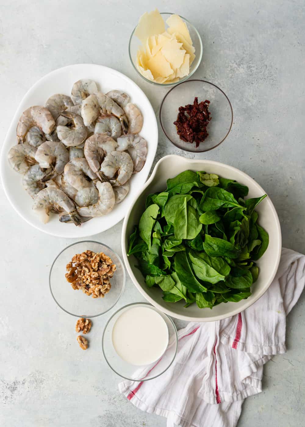 ingredients for an easy shrimp recipe, including shrimp, spinach, parmesan, sun dried tomatoes and walnuts
