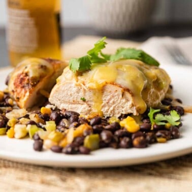 A close up of a plate of food on a table, with Chicken breast on black beans
