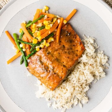 A plate of food with rice grilled salmon and vegetables