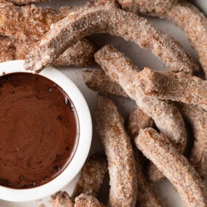 fried churros next to melted chocolate dipping sauce