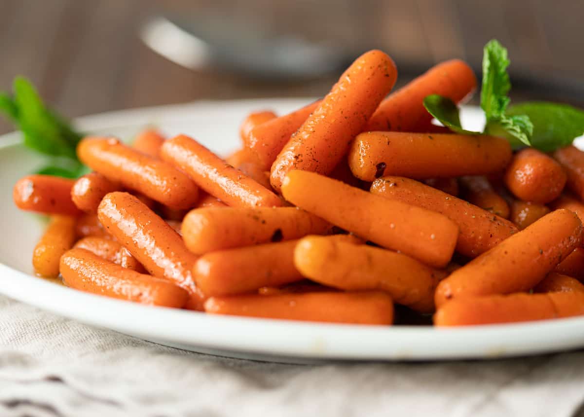 plate of brown sugar glazed sauteed baby carrots with fresh mint garnish