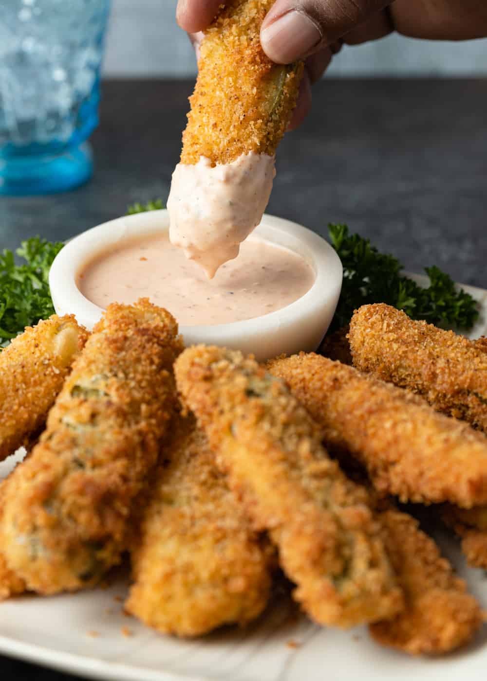 dipping fried pickle spears into dipping sauce