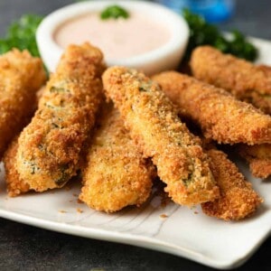 deep fried pickle spears on white plate with homemade dipping sauce