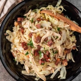overhead photo: shredded chicken and cabbage in a wok with wooden spoon