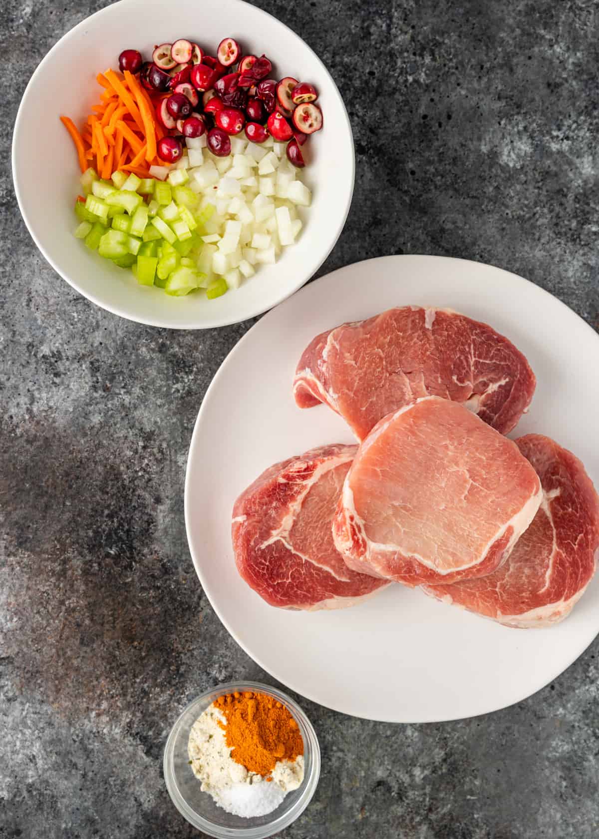 A bowl of diced vegetables on a plate, with Pork chops