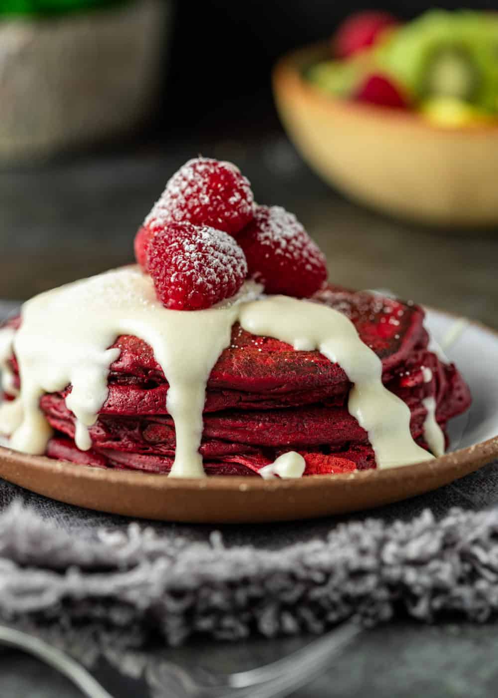 small stack of red pancakes for two topped with sweet sugar glaze and fresh raspberries