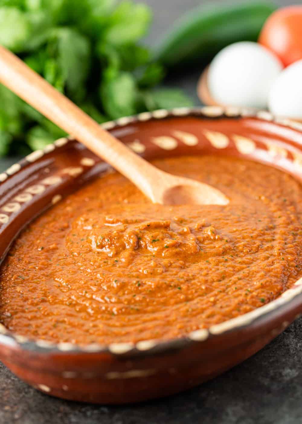 Red ranchero sauce in large bowl with wooden spoon