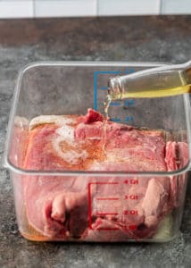 pouring olive oil into container with carne asada meat
