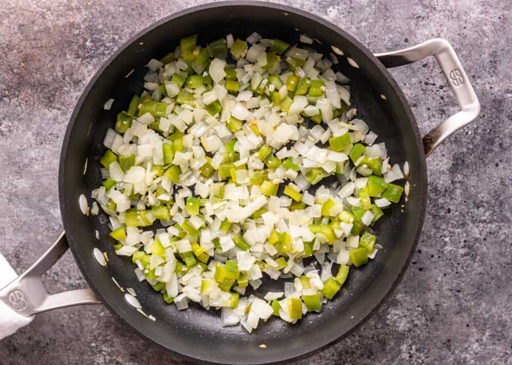overhead: sauteing diced onions and green bell peppers in skillet