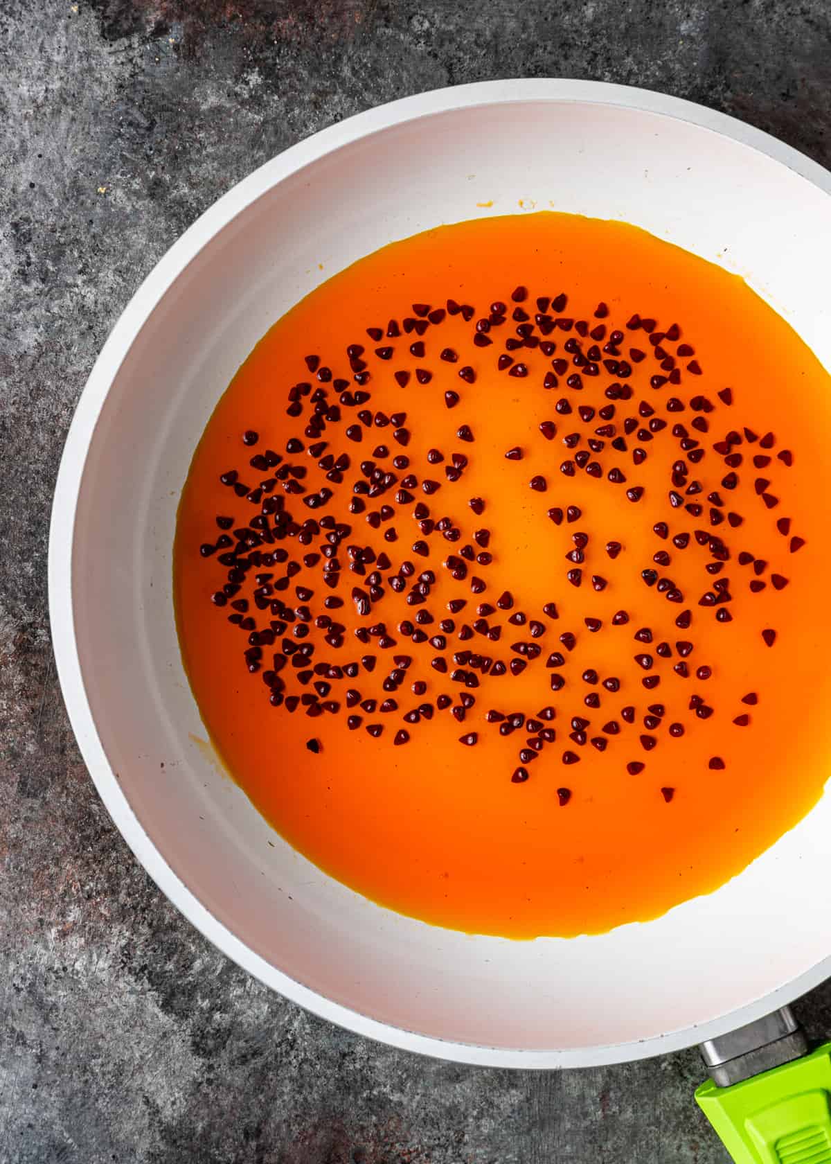 annatto seeds steeped in oil in frying pan