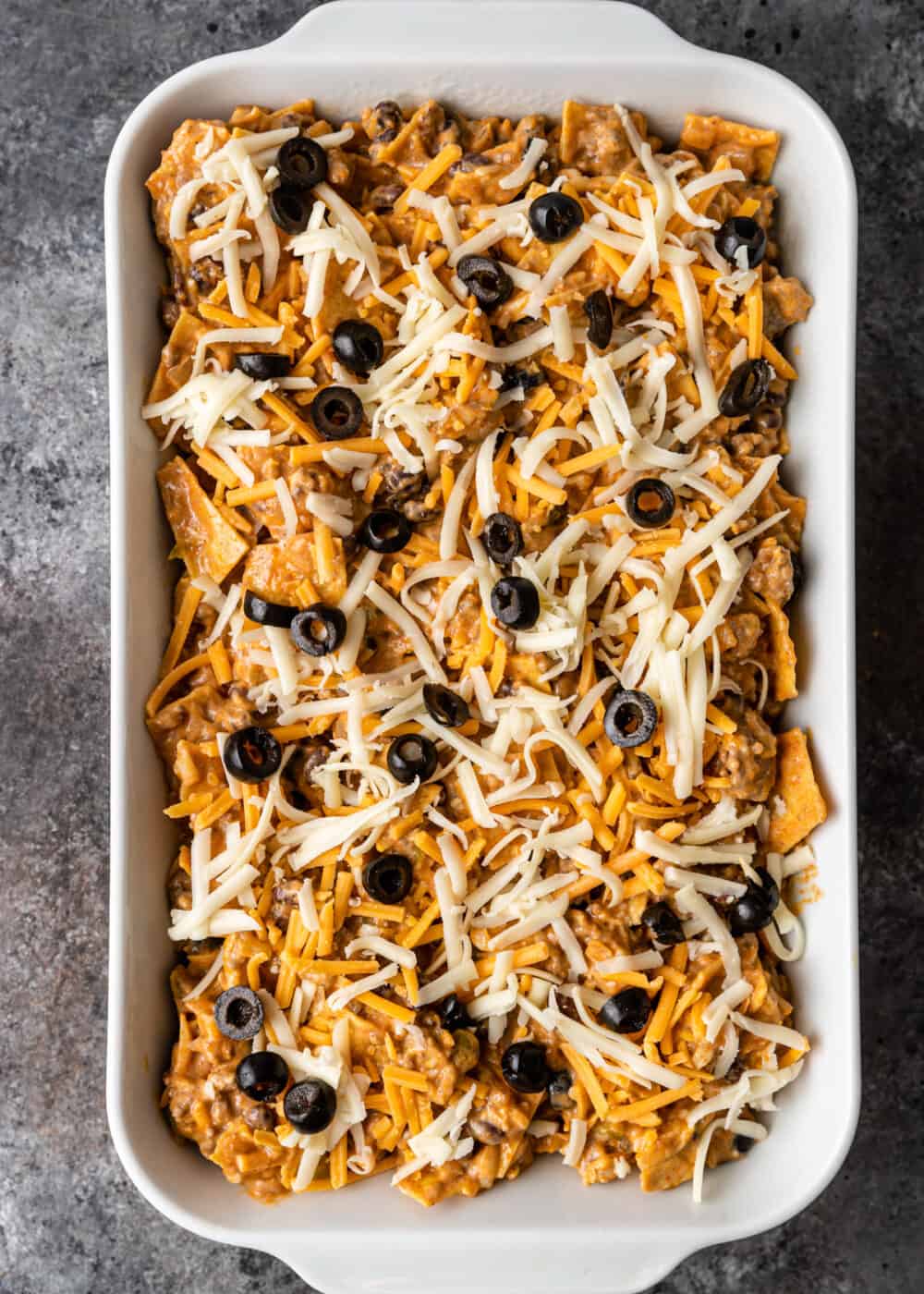 overhead; shredded cheese, black olives and tortillas in casserole dish