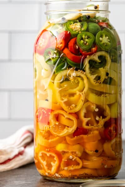 large mason jar with red yellow and green pickled peppers