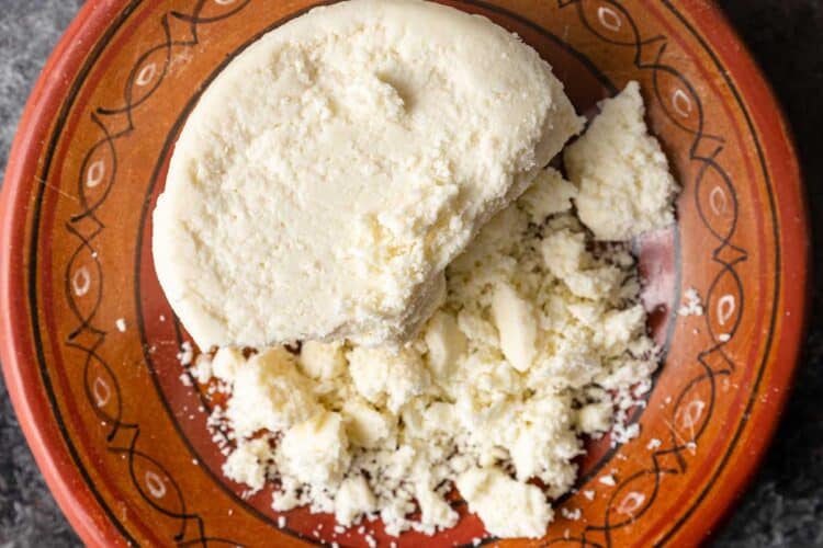 cotija cheese round and crumbled on plate