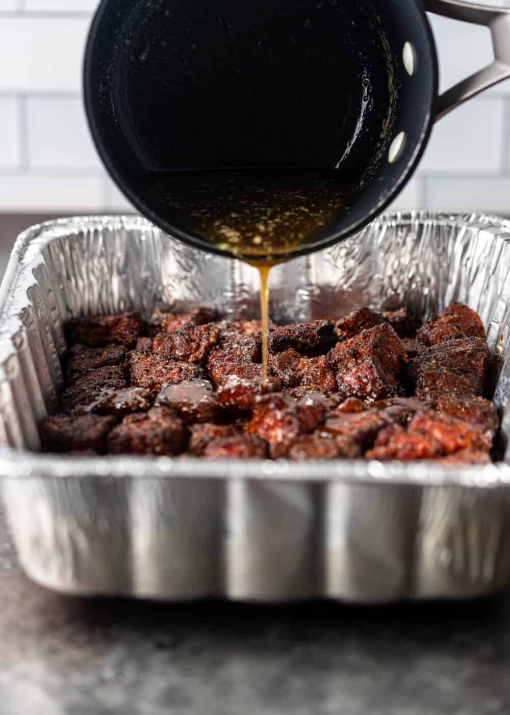pouring sauce on the Pork Belly Burnt Ends