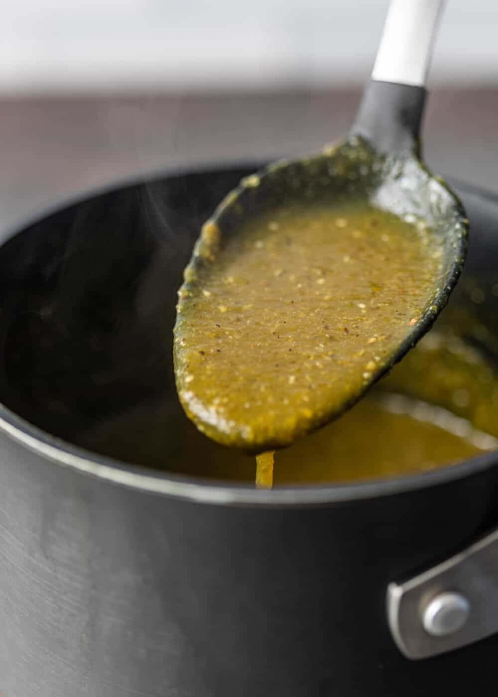 extreme closeup: a spoonful of this Serrano hot sauce recipe over a saucepan with more sauce