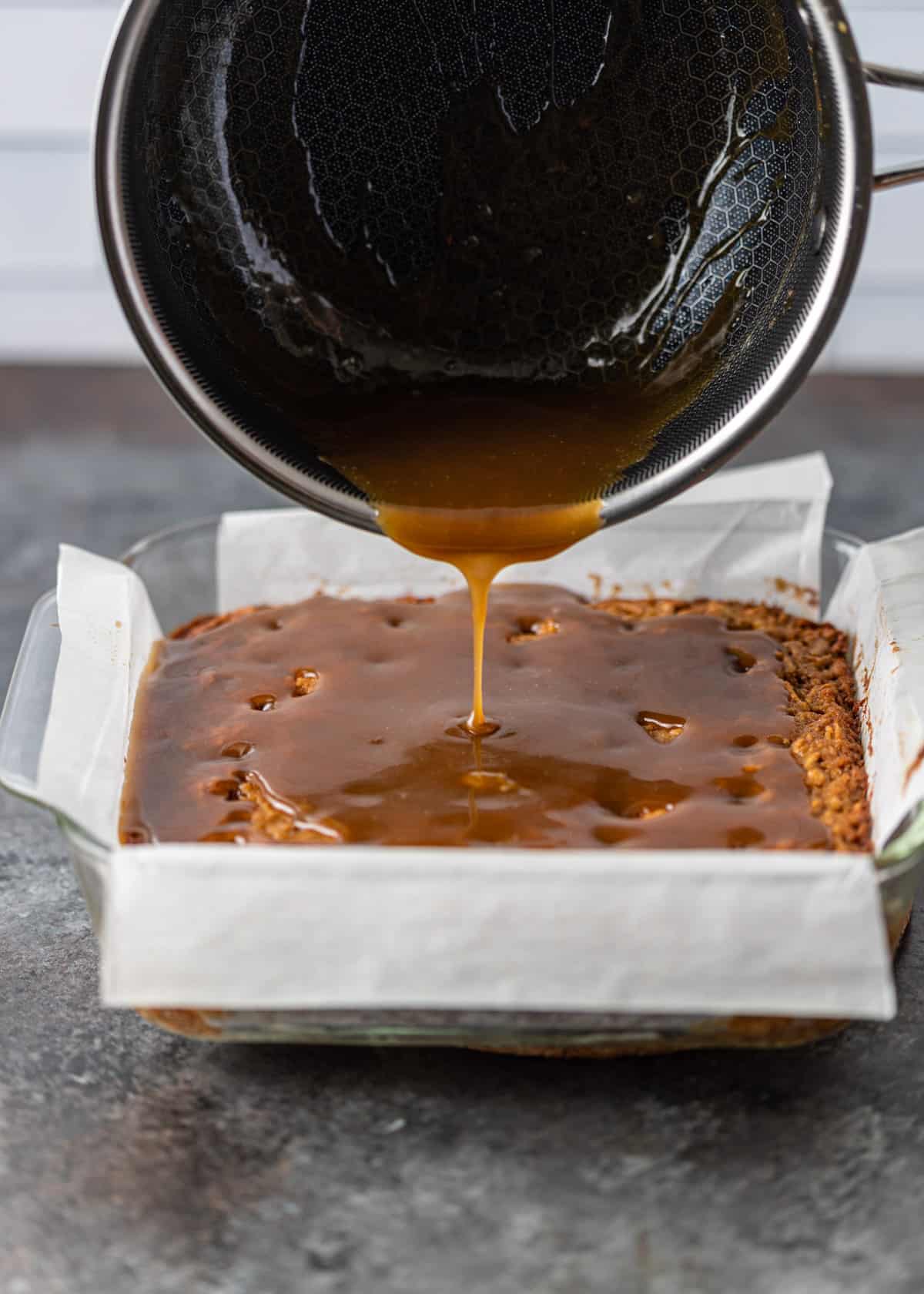 pouring caramel topping over apple poke cake