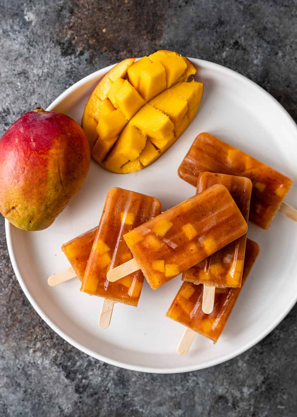 overhead of a plate full of mango paletas with a cut mango