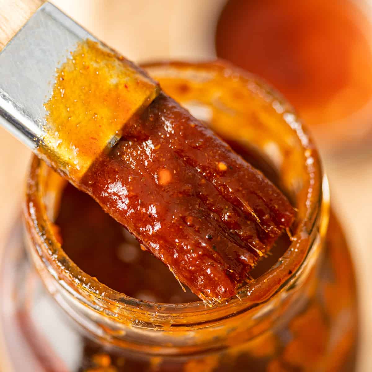 close up of homemade BBQ sauce recipe on a brush over a jar