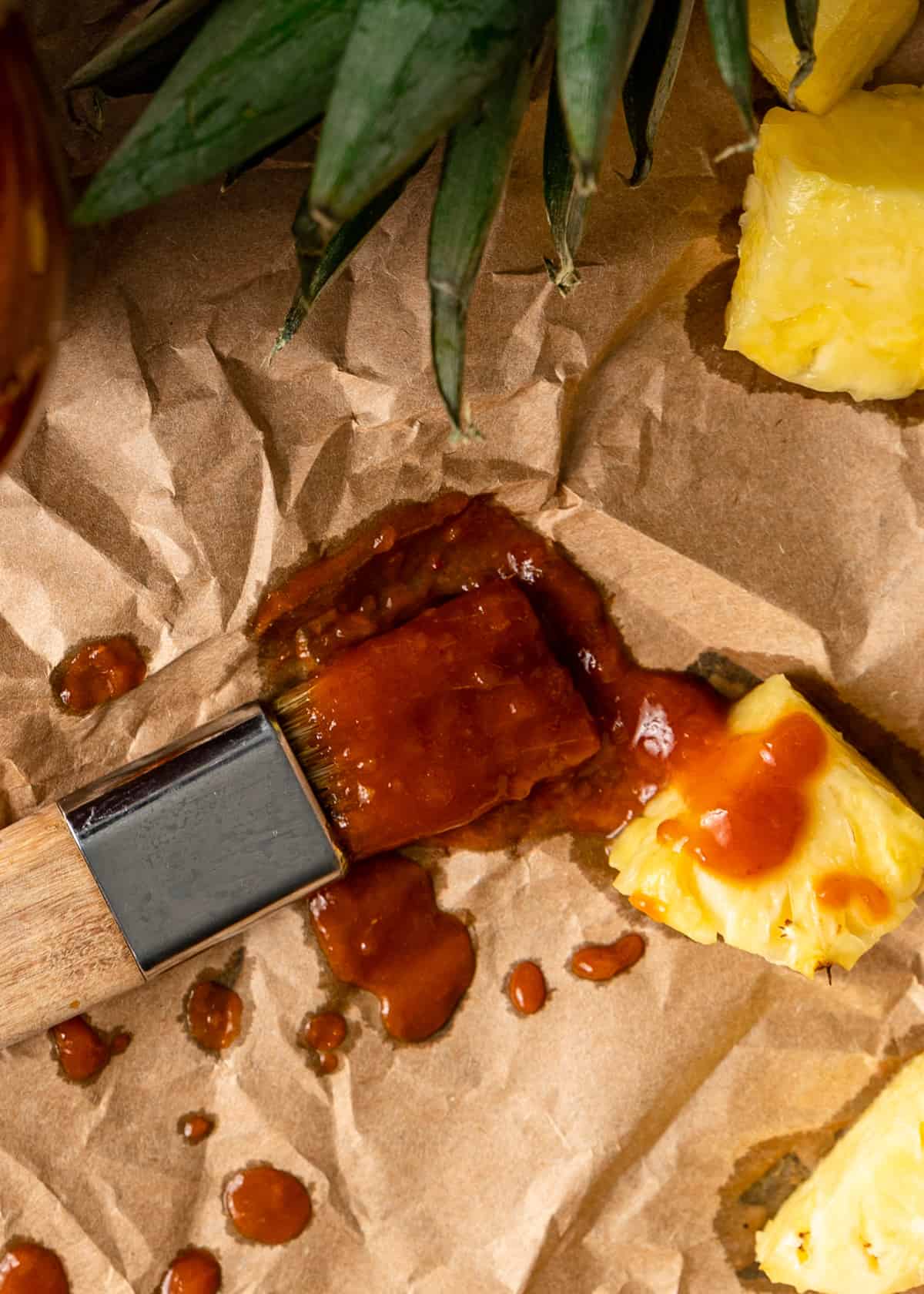 a brush with pineapple barbecue sauce and butter on a piece of parchment