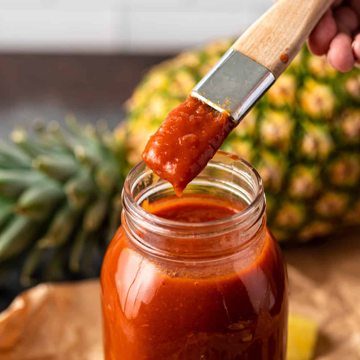 pineapple BBQ sauce in a glass jar with a brush with sauce on it