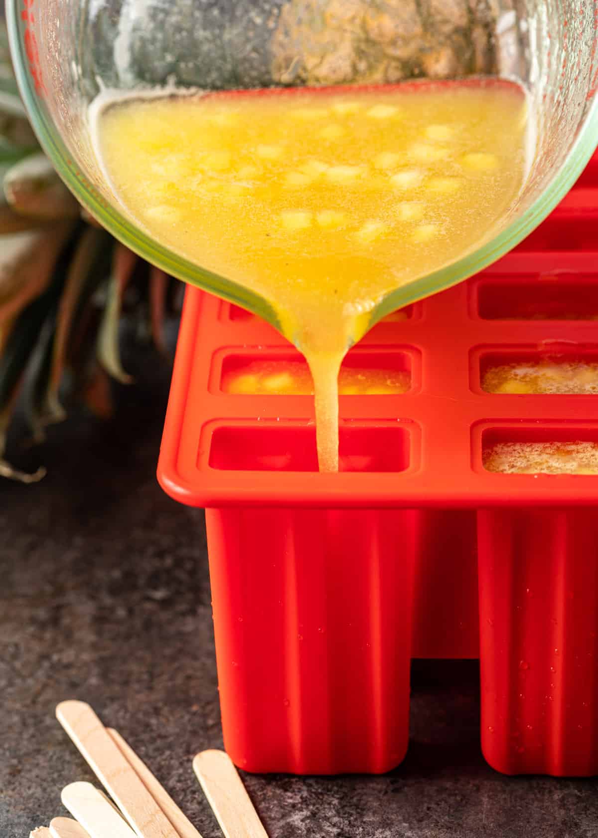 pouring pineapple ice pops into a mold
