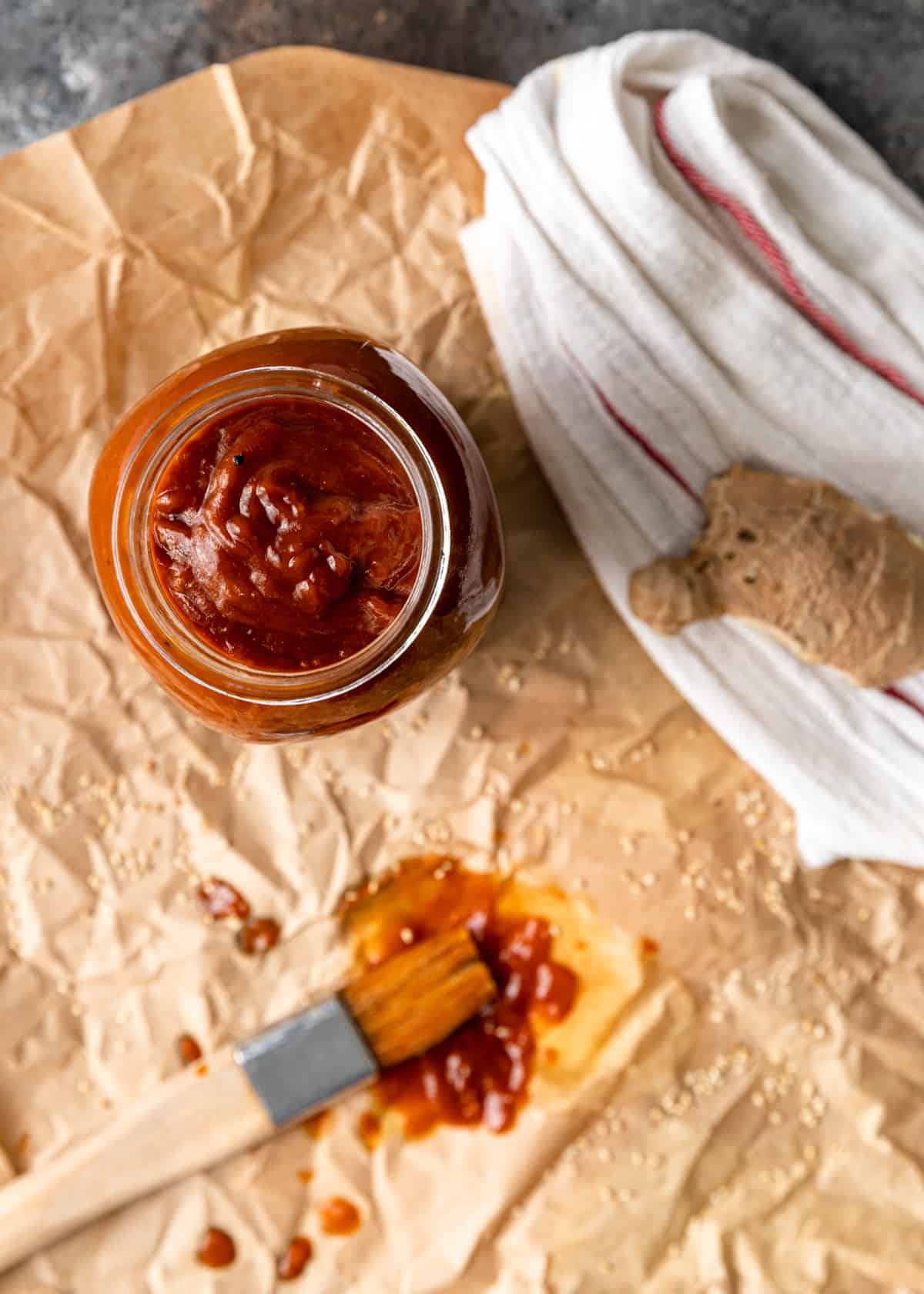 overhead: sesame ginger BBQ sauce in a glass jar with fresh ginger visible to the right