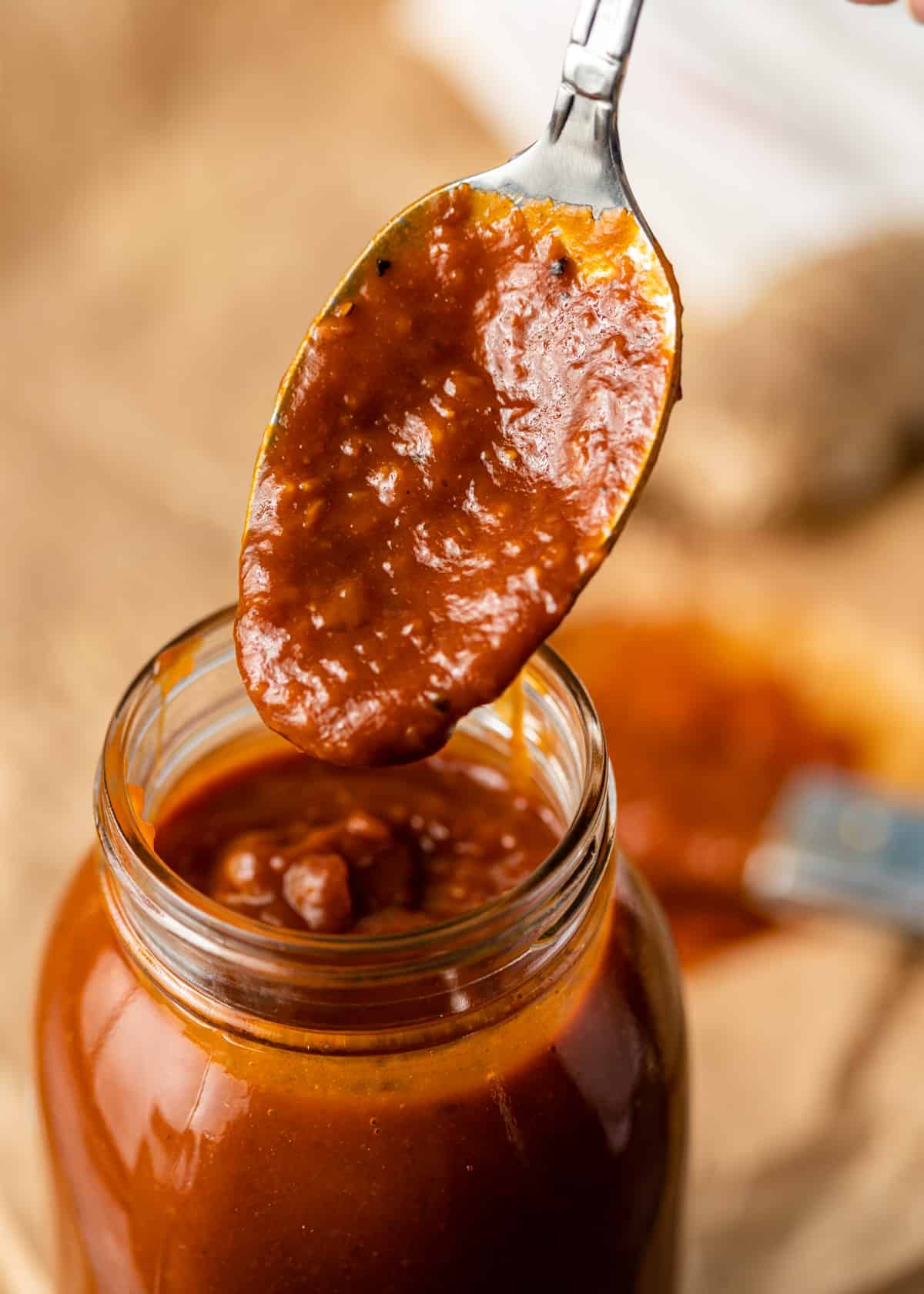closeup: a spoon full of sesame ginger BBQ sauce over a glass jar