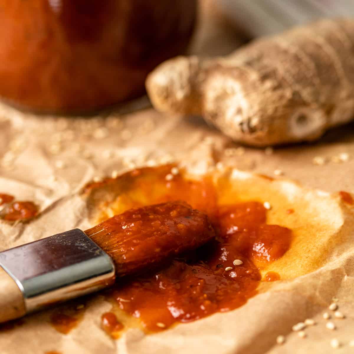 a brush with sesame ginger BBQ sauce and fresh ginger visible in the background
