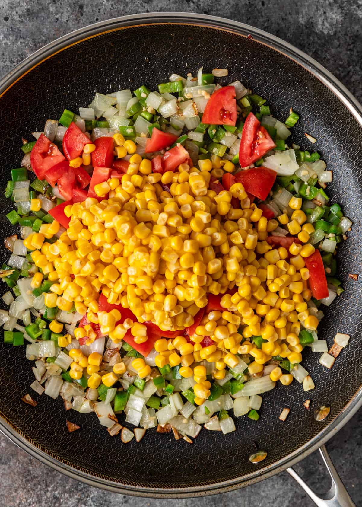 overhead: sautéing onions, peppers, corn, and tomatoes