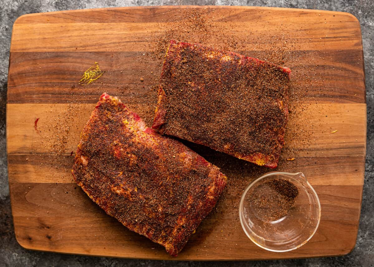 overhead: seasoned beef back ribs on a wooden cutting board before smoking